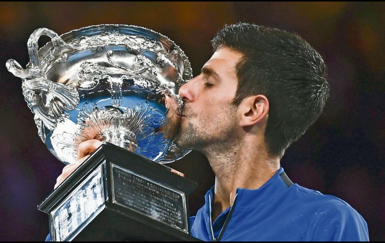 Novak Djokovic besa su trofeo tras ganar por séptima ocasión el Abierto de Australia. AFP