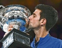 Novak Djokovic besa su trofeo tras ganar por séptima ocasión el Abierto de Australia. AFP