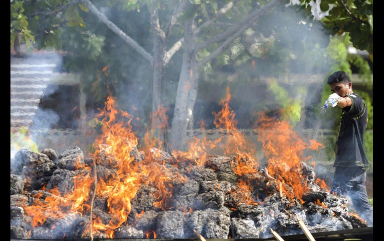 Un integrante de la Agencia Nacional Antidrogas indonesia rocía combustible para quemar 515 kilos de mariguana decomisada, durante una ceremonia en Banda Aceh. AFP/C. Mahyuddin