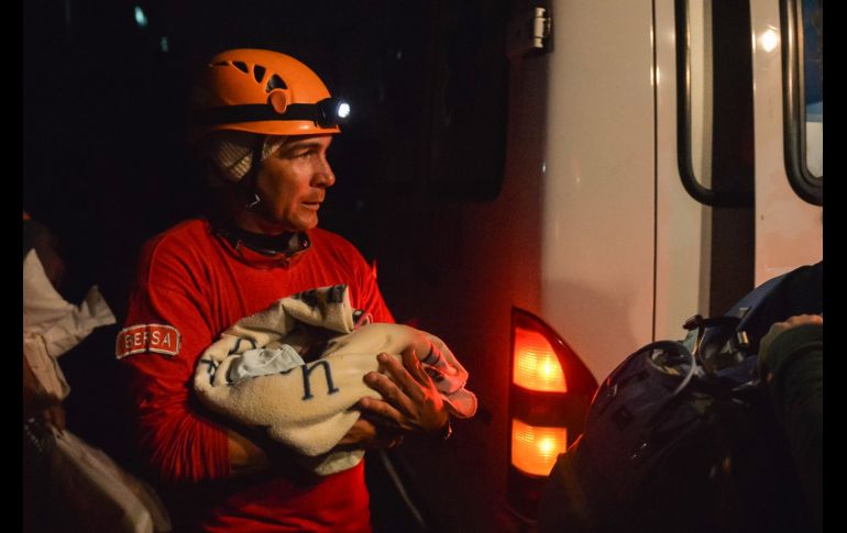 Un bombero sostiene a un bebé durante labores de evacuación.