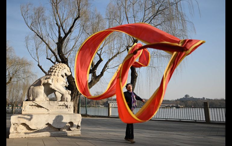 Una anciana baila con un listón en un parque en Pekín, China. AFP/W. Zhao