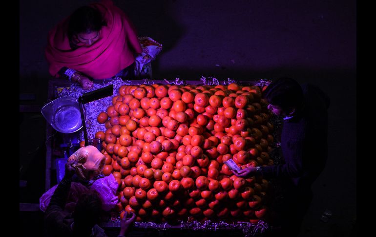 Una mujer compra naranjas a un vendedor callejero en Nueva Delhi, India. AFP/S. Hussain