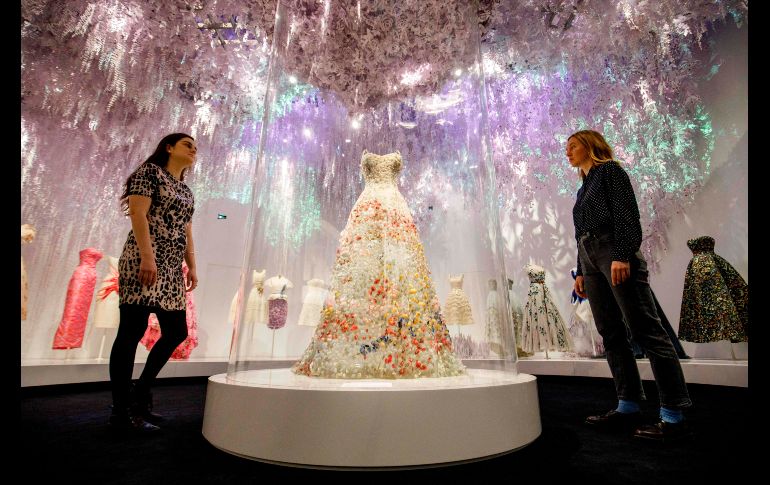 Asistentes posan junto a un vestido de Maria Grazia Chiurie, parte de la exposición 