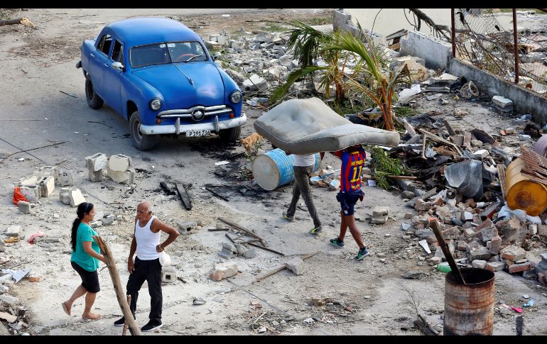 Dos personas llevan un colchón en una calle del barrio de Luyano en La Habana, Cuba. Casi cinco mil personas permanecen evacuadas tras el intenso tornado que tomó por sorpresa a la capital cubana, y dejó cuatro muertos y 195 heridos. EFE/E. Mastrascusa