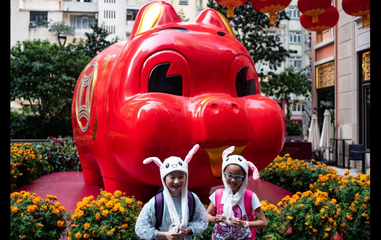 Niños posan frente a una instalación de un cerdo gigante en Hong Kong, previo a las celebraciones del Año Nuevo lunar chino, que este 2019 es del cerdo. AFP/P. Fong