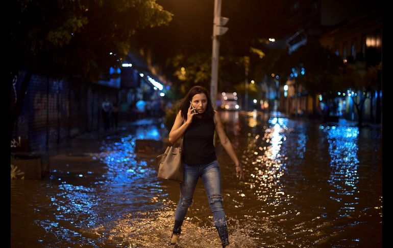 Una mujer camina por una calle inundada en el vecindario Botafogo de Río de Janeiro, luego de fuertes lluvias. AFP/M. Pimentel