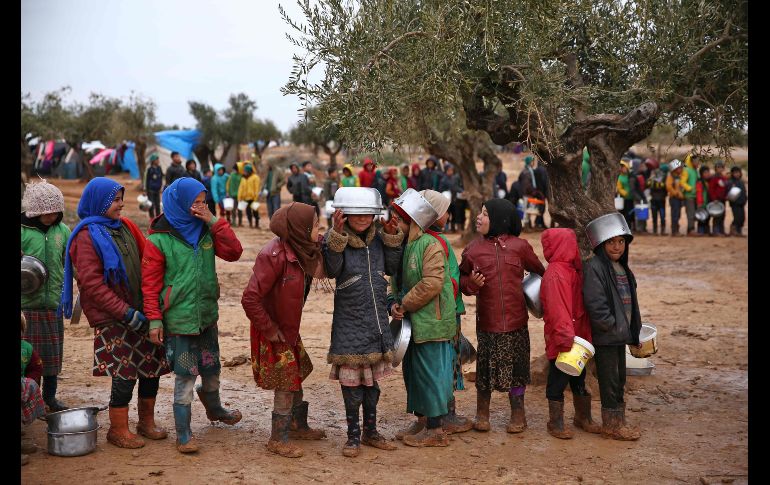 Niños hacen fila para recibir alimentos distribuidos por trabajadores de ayuda humanitaria en un campamento para desplazados en Yazi Bagh, Siria. AFP/N. Al-Khatib