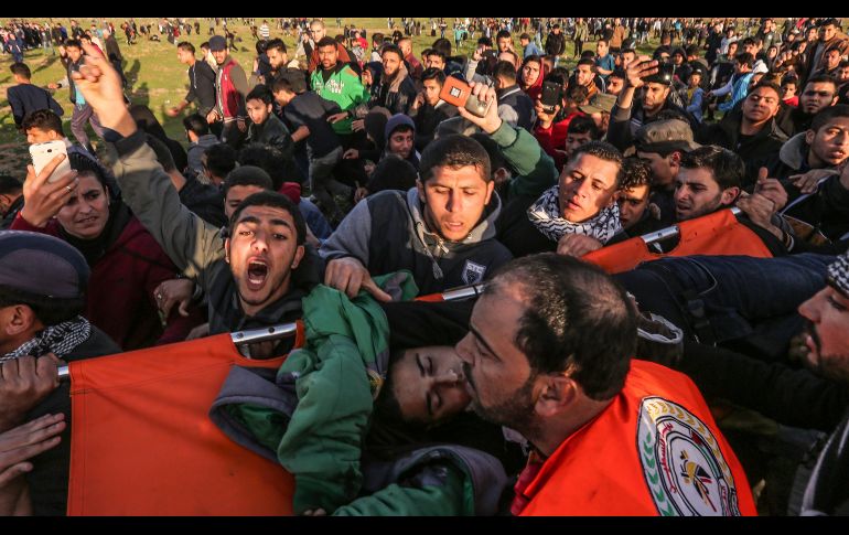 Palestinos evacuan a un hombre herido durante una manifestación en la Ciudad de Gaza, cerca de la reja fronteriza con Israel. En enfrentamientos hoy, dos palestinos resultaron muertos por fuego israelí. AFP/M. Hams