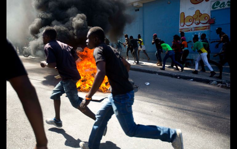 Manifestantes pasan una barricada junto a una bodega que fue saqueada en Puerto Príncipe, Haití, durante protestas en demanda de la renuncia del presidente Jovenel Moise. AP/D. Nalio Chery