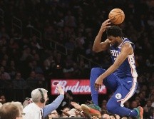 Joel Embiid intenta rescatar un balón y salta sobre el público. AP