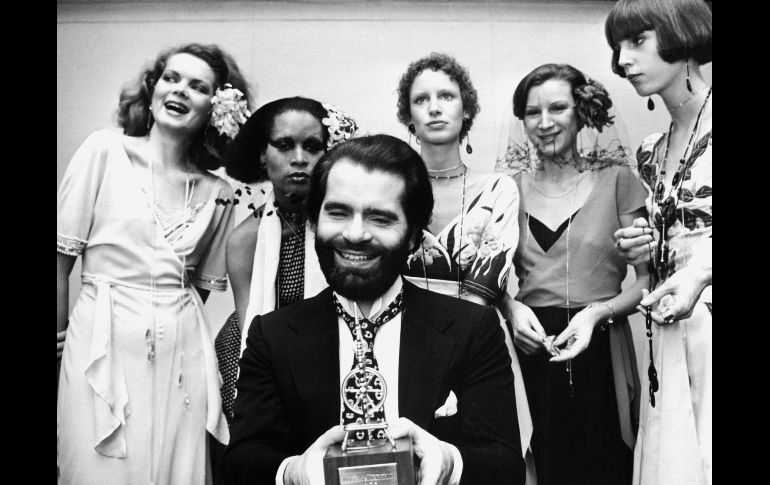 El diseñador aparece en una foto tomada el 29 de noviembre de 1973, durante un desfile en Alemania; se encuentra rodeado de las mejores modelos del momento. AFP