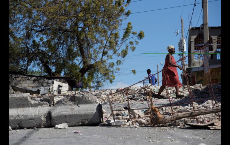 Una mujer camina por una calle cubierta por escombros y basura, producto de las violentas protestas de la semana pasada, en Puerto Príncipe, Haití. Desde esta semana el país está en aparente calma, por lo que los bancos comerciales y muchos negocios, cerrados desde el inicio de las protestas, reabrieron el lunes y un día después lo hicieron las escuelas y los colegios. EFE/O. Barría