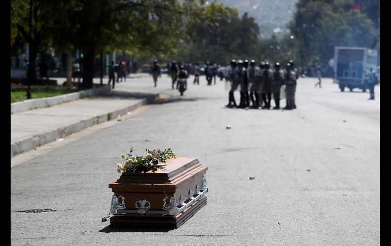 El ataúd con los restos de un hombre abatido durante las violentas manifestaciones se ve en el suelo en Puerto Príncipe, Haití, mientras policías impiden el paso del cortejo fúnebre ante nuevas manifestaciones. REUTERS/I. Alvarado