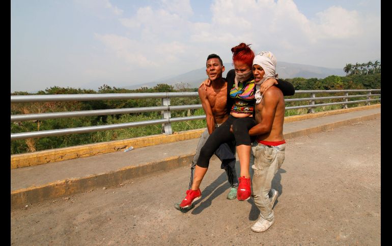 Opositores venezolanos cargan en Cúcuta a una mujer herida en los choques con militares.