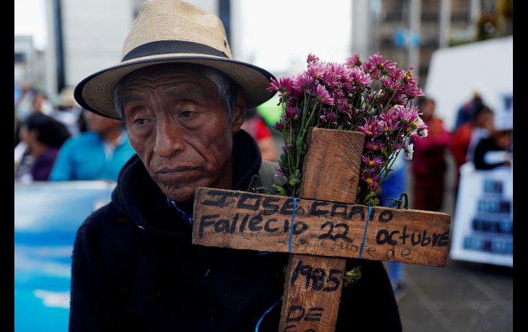 Un hombre carga una cruz con la inscripción del nombre y fecha de un familiar muerto en la guerra interna, durante una manifestación en Ciudad de Guatemala con motivo del Día Nacional de la Dignificación de las Víctimas del Conflicto Armado. EFE/E. Biba
