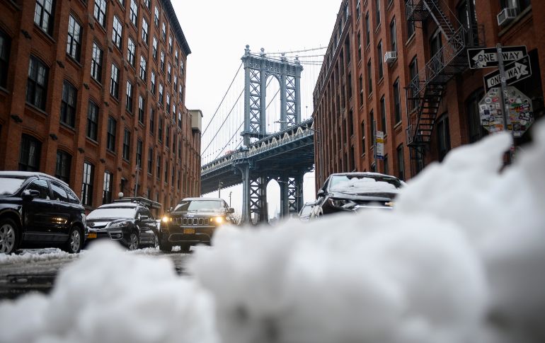 Autos circulan junto a un montón de nieve enfrente del puente Manhattan en Nueva York, tras una nevada que llevó a suspender las clases este lunes en la ciudad. AFP/J. Eisele