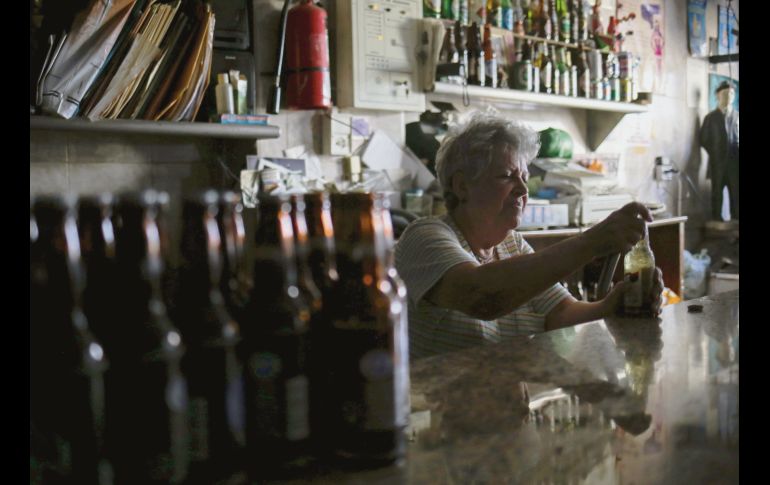 Para que el trago por la falta de energía sea menos amargo, una mujer destapa una cerveza y la bebe. AFP