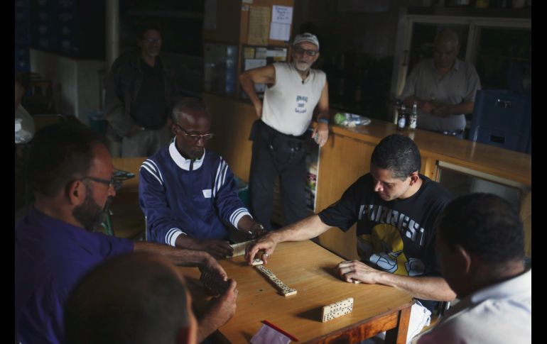 Un grupo de amigos disfruta de una partida de dominó... hasta que la luz del día se los permita. AFP