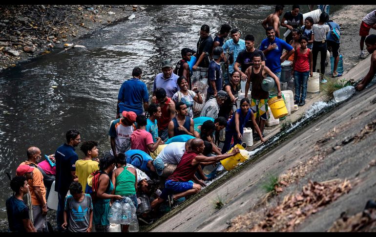 Habitantes de Caracas llevaron baldes y garrafones para recoger agua del río Guaire. AFP/J. Barreto