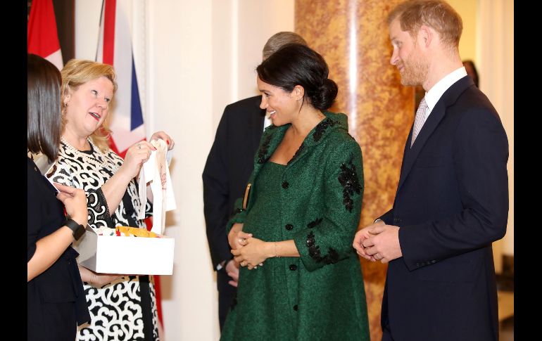 El príncipe Enrique de Inglaterra y su esposa Meghan, duquesa de Sussex, reaccionan al recibir regalos para su bebé de parte de Janice Charette (2 i), alta comisionada de Caná en Reino Unido, en Canada House, durante un evento en Londres por el Día de la Commonwealth. AFP/C. Jackson