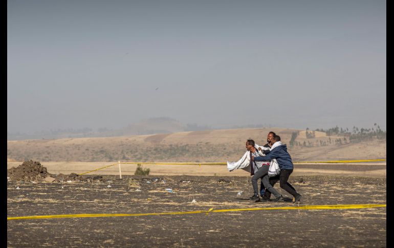Hombres detienen a otro en el sitio donde murió un familiar, víctima del accidente aéreo del domingo,  cerca de la ciudad etíope de Bishoftu.