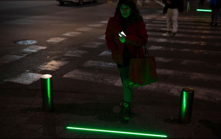 Una mujer pasa a través de las luces LED, que se tornaron verdes, mientras sostiene su teléfono. AP/S. Scheiner