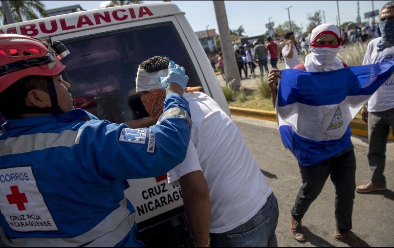 Un manifestante es atendido por miembros de la Cruz Roja después de haber recibido un disparo de bala de goma en la cabeza. EFE/J. Torres