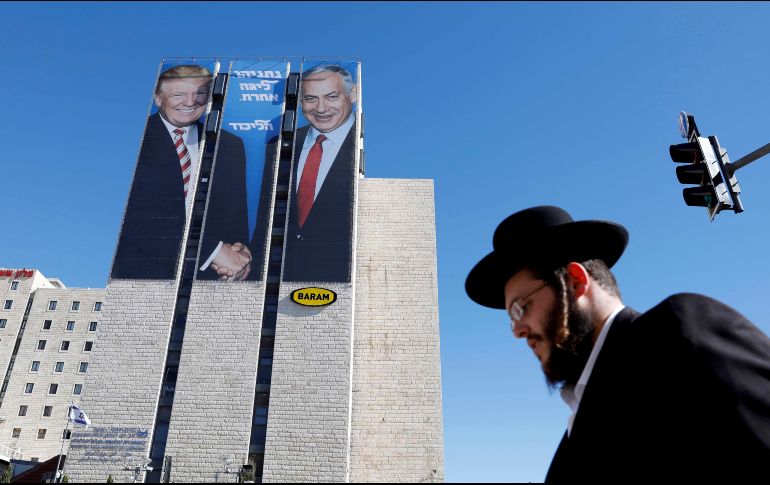 Un judío ultra ortodoxo pasa junto a carteles con la imagen del presidente estadounidense, Donald Trump (i), y el primer ministro israelí, Benjamín Netanyahu (d), en Jerusalén. EFE/A. Sultan