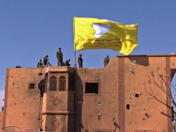 Milicianos de las Fuerzas de Siria Democrática izan su bandera en el territorio hasta hace poco controlado por el EI. AFP/RONAHI TV