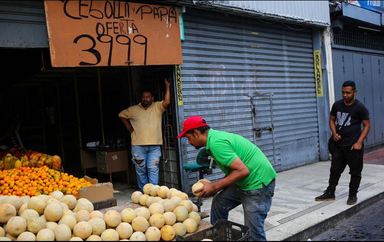 Un vendedor de frutas y verduras acomoda su mercancía en un mercado de Caracas. AFP/C. Hernández