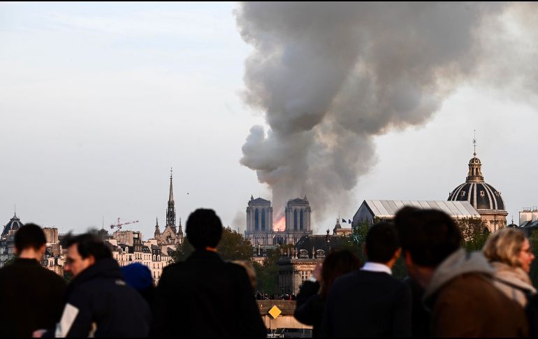 Parisinos y turistas ven el fuego que consume uno de sus lugares más emblemáticos. AFP / P. Lopez