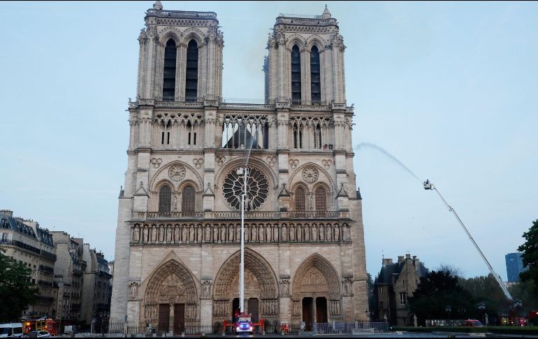 Miembros de la brigada de bomberos de París rocían agua sobre la fachada de la catedral de Notre Dame este lunes, en París. EFE/P. Wojazer