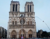 Miembros de la brigada de bomberos de París rocían agua sobre la fachada de la catedral de Notre Dame este lunes, en París. EFE/P. Wojazer