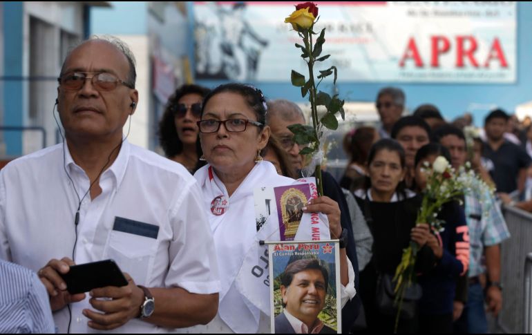 Una mujer con una foto del expresidente Alan Garía aguarda este viernes para entrar al local del partido donde se realiza el funeral en Lima, Perú. AP/M. Mejía