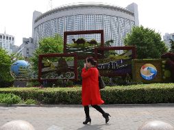 Una mujer pasa frente al Ministerio de Relaciones Exteriores chino, decorado con motivo de la reunión. AP/N. Guan
