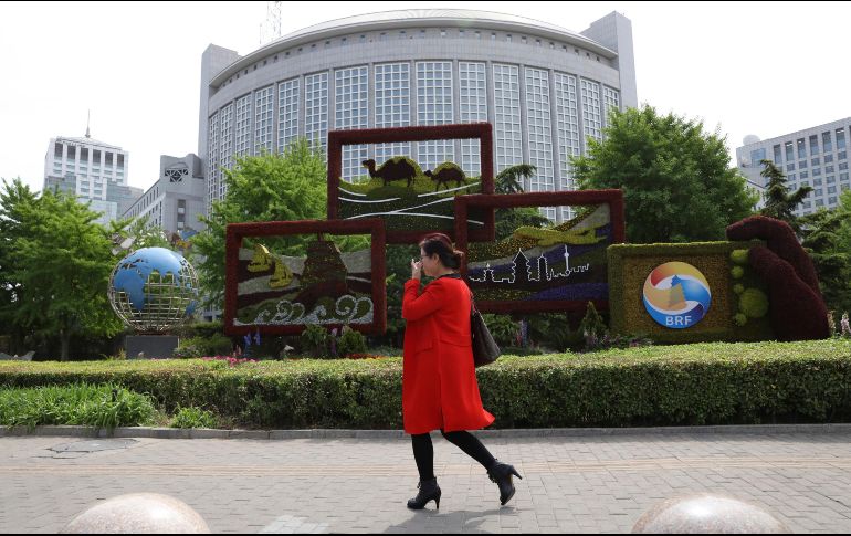 Una mujer pasa frente al Ministerio de Relaciones Exteriores chino, decorado con motivo de la reunión. AP/N. Guan