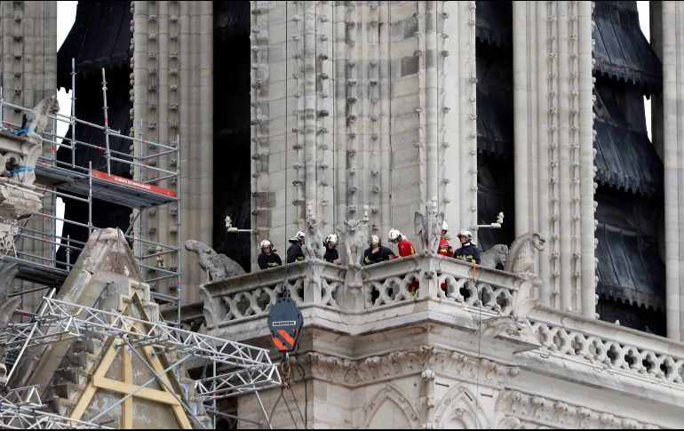 Trabajadores con cascos blancos hablaban con los bomberos ante el monumento, mientras otros apuntalaban la catedral del siglo XII. Ya había varias grúas alrededor de la estructura. AP / T. Camus