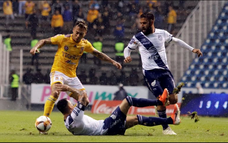 Los jugadores de Puebla, Lucas Cavallini (abajo) y Pablo González (d), disputan la bola con Eduardo Vargas (i), de Tigres. EFE/H. Ríos