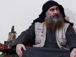 Abu Bakr al Bagdadi aparece sentado en el suelo, sobre unos cojines y con las piernas cruzadas; a su lado se puede ver un rifle apoyado en una pared. TWITTER/@laleyro