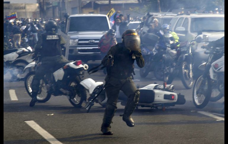 Elemento de la Guardia Nacional huyen entre el gas lacrimógeno. AFP/Y. Cortez
