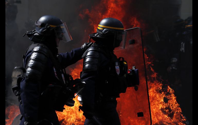 Policías pasan junto a una barricada en llamas. EFE/I. Langsdon