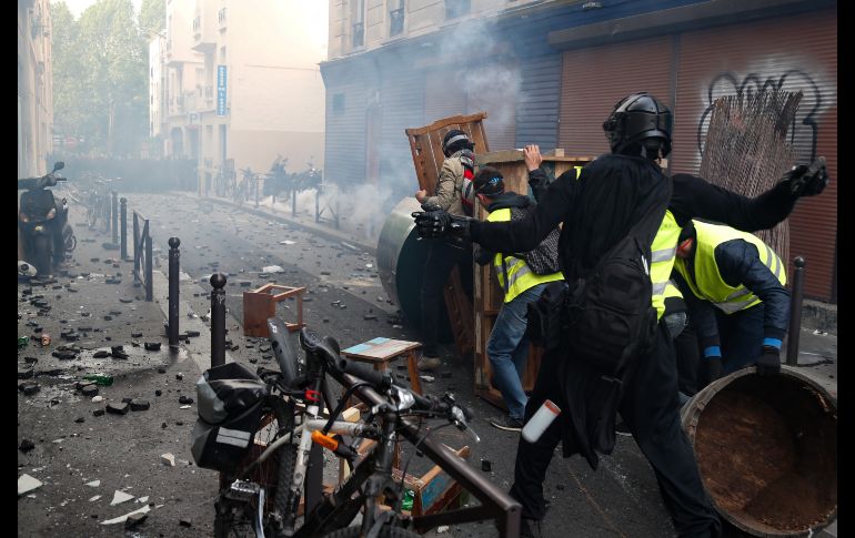 Manifestantes arrojan piedras detrás de una barricada en el marco de los enfrentamientos en París. AFP/Z. Abdelkafi
