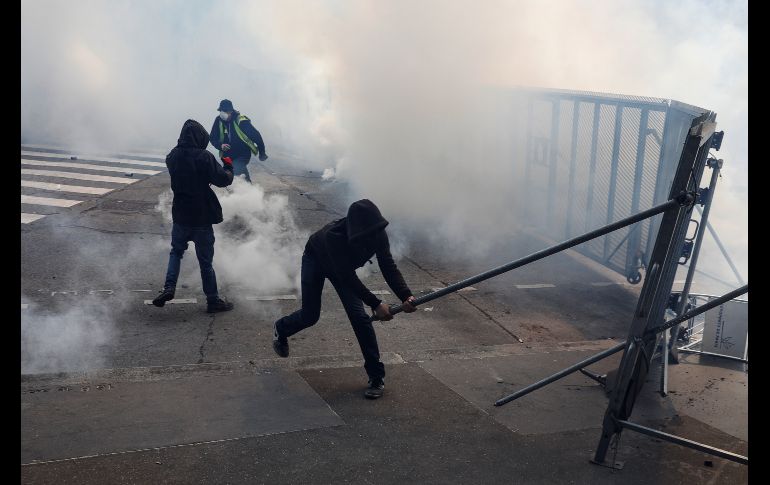 Manifestantes intentan tumbar una barrera que rodea una estación policial. AFP/G. Van Der Hasselt