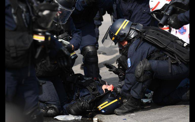 Policías atienden a un compañero herido. AFP/M. Bureau
