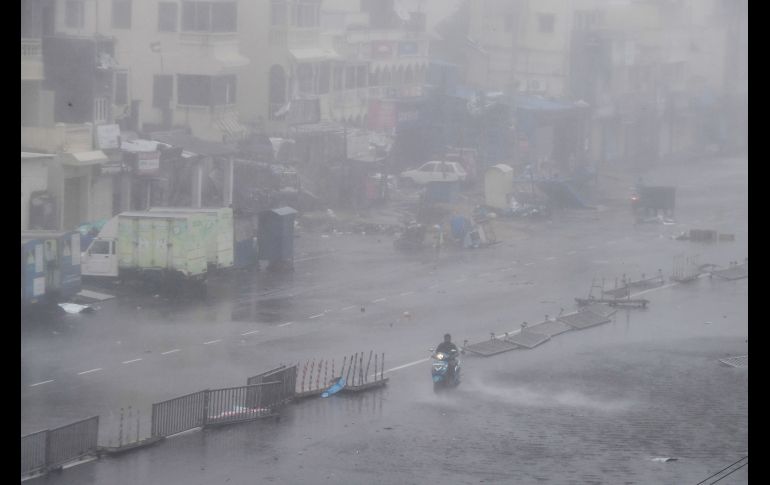 Un habitante circula en moto por una calle inundada y con escombros en Puri. AFP/D. Sarkar