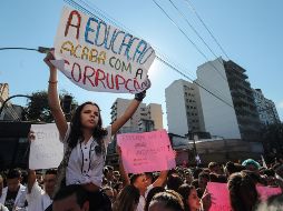 Una joven sostiene un cartel en el que se lee 