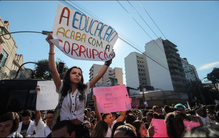 Una joven sostiene un cartel en el que se lee 