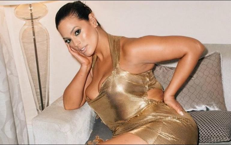 Graham aparece en una de las imágenes sentada en un sofá luciendo un corto vestido dorado que deja al descubierto sus piernas. INSTAGRAM / ashleygraham