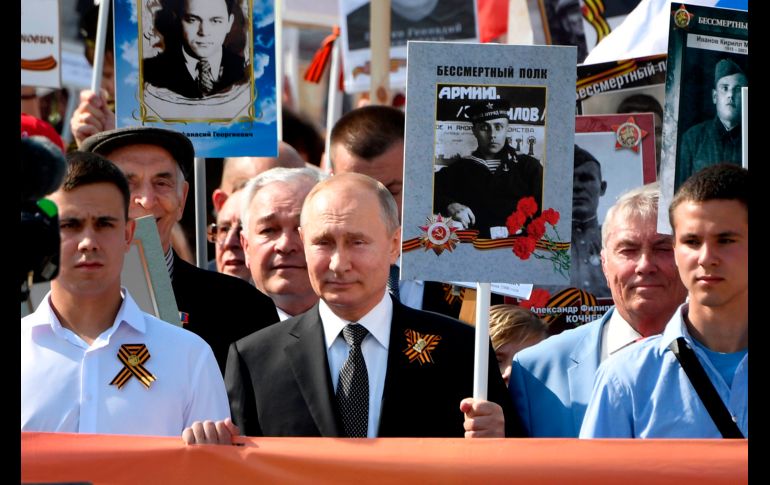 El presidente Vladimir Putin (c) marcha con habitantes que portan retratos de familiares que combatieron en la contienda.