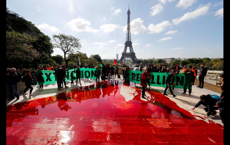 Miembros de Extinction Rebellion desplegaron letreros frente a la Torre Eiffel tras derramar la sangre falsa.